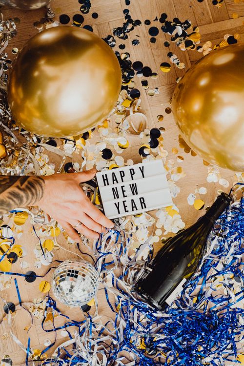 Free Colorful New Year party scene with balloons, confetti, and a Happy New Year sign. Stock Photo