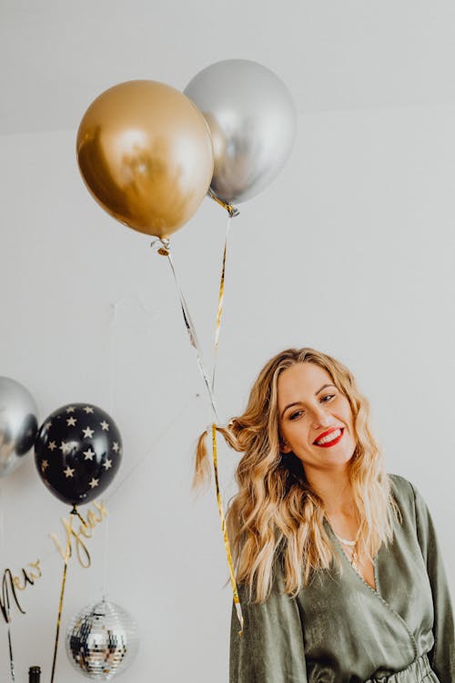 Smiling Woman with Balloons Filled with Helium Attached to Her Hair