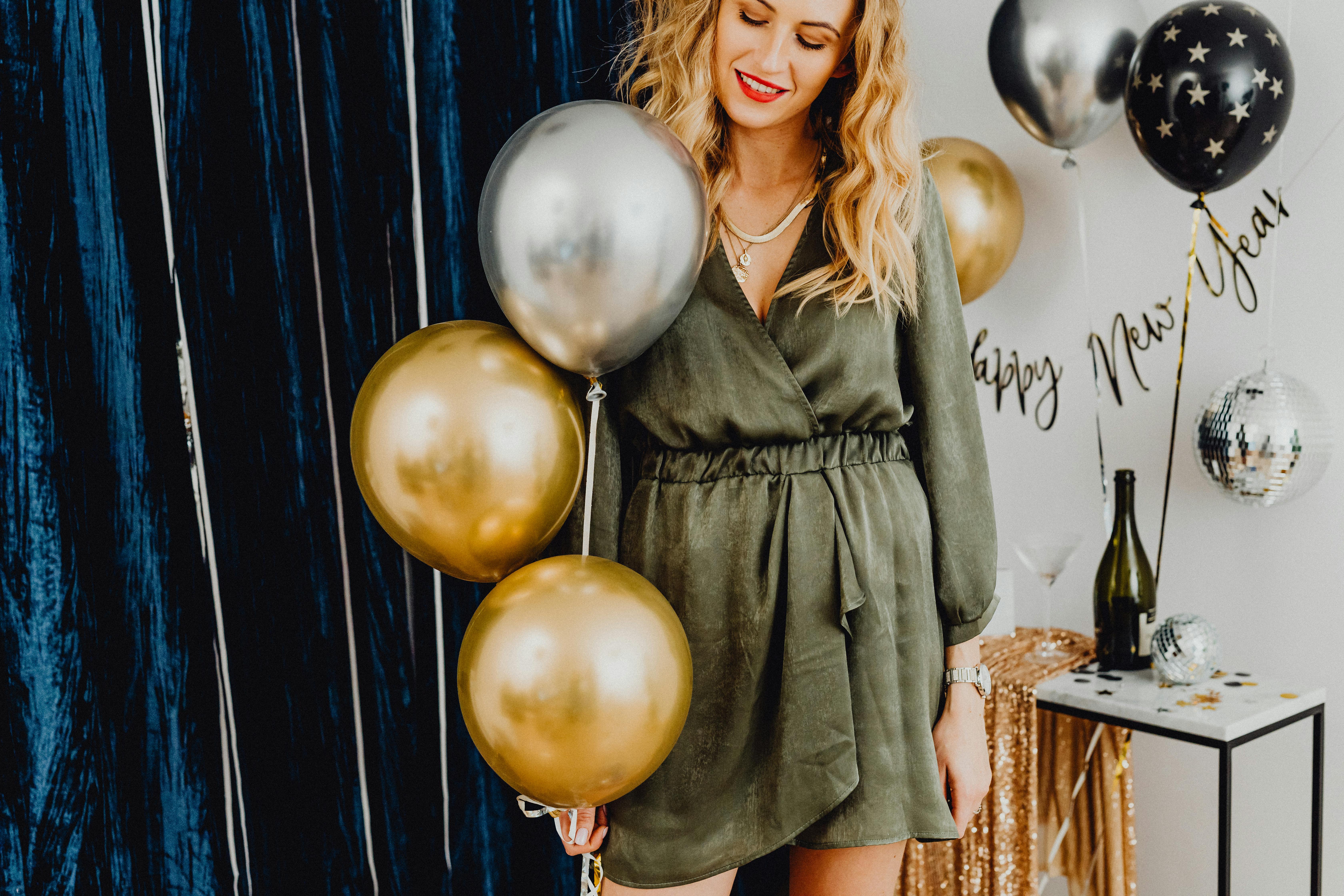 smiling woman holding balloons at a new years eve party