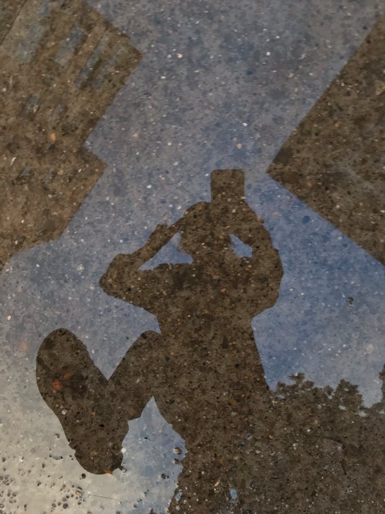 Reflection Of Walking Person In Puddle Water 