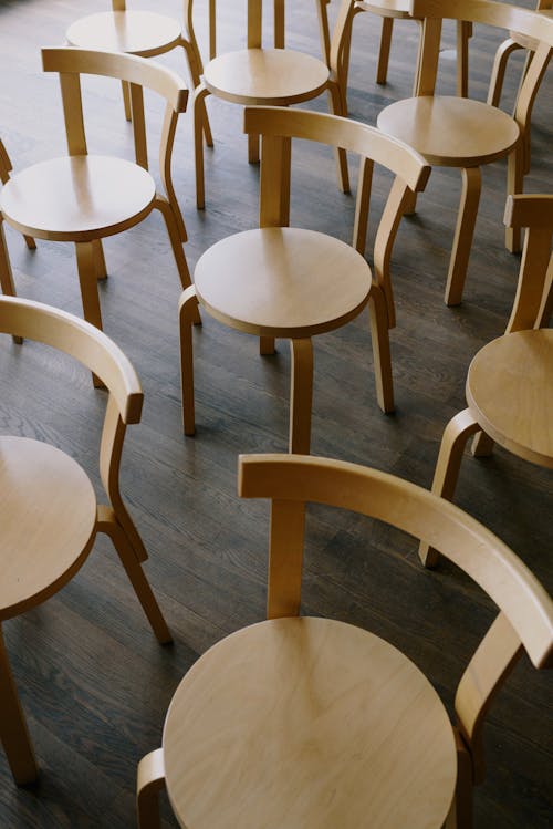 From above of wooden round chairs placed on parquet floor in room for occasion