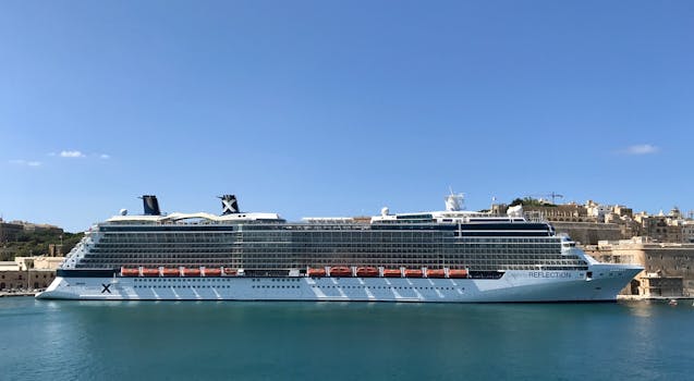 Modern luxury cruise ship moored on sea water in old town port against cloudless blue sky