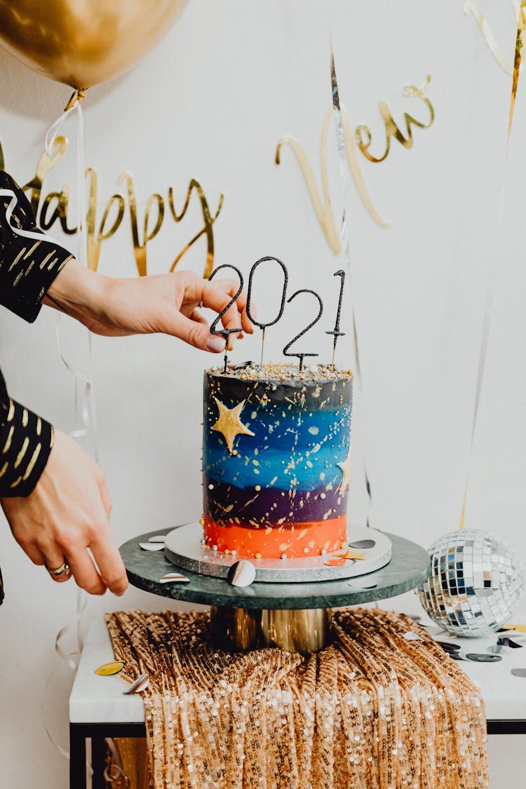 Person Putting Number Candles On Top Of The Cake 