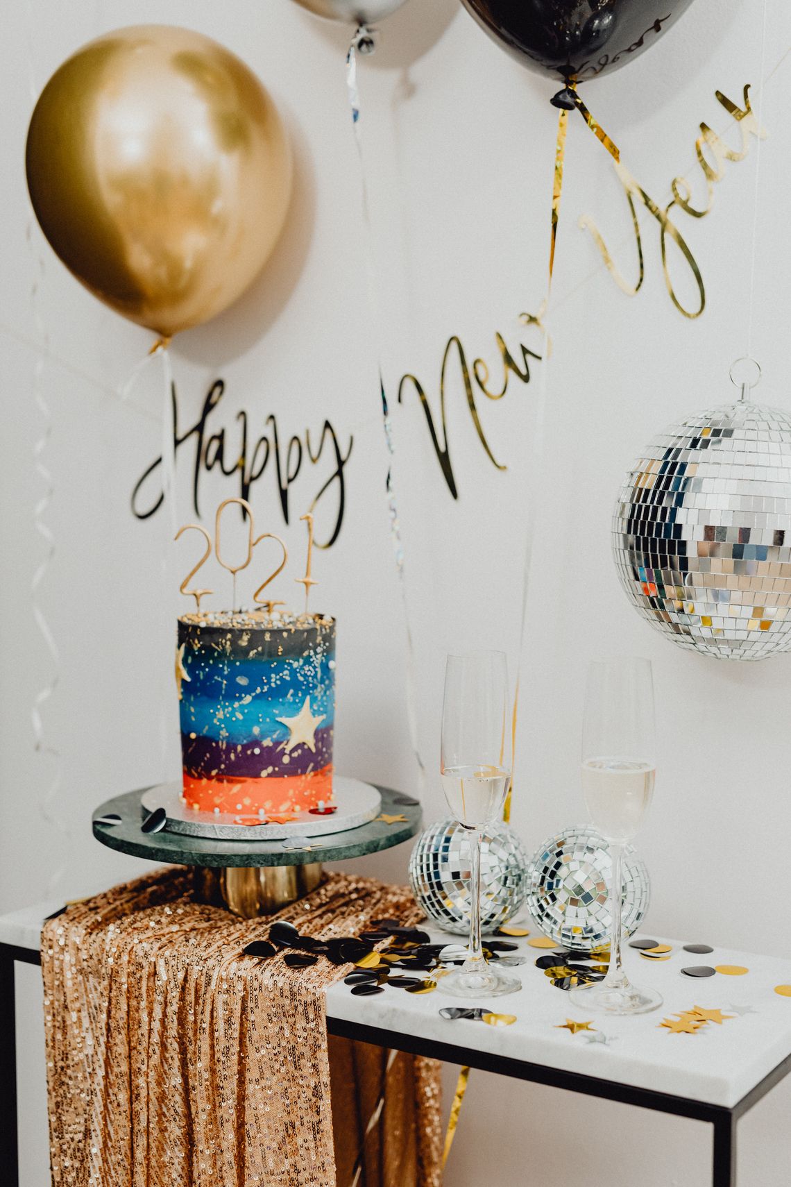 Glamorous celebration table with disco balls, cake, balloons, and sparkling party details