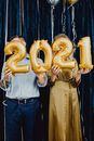 两人欢乐地握着金色的“2021”气球庆祝新年