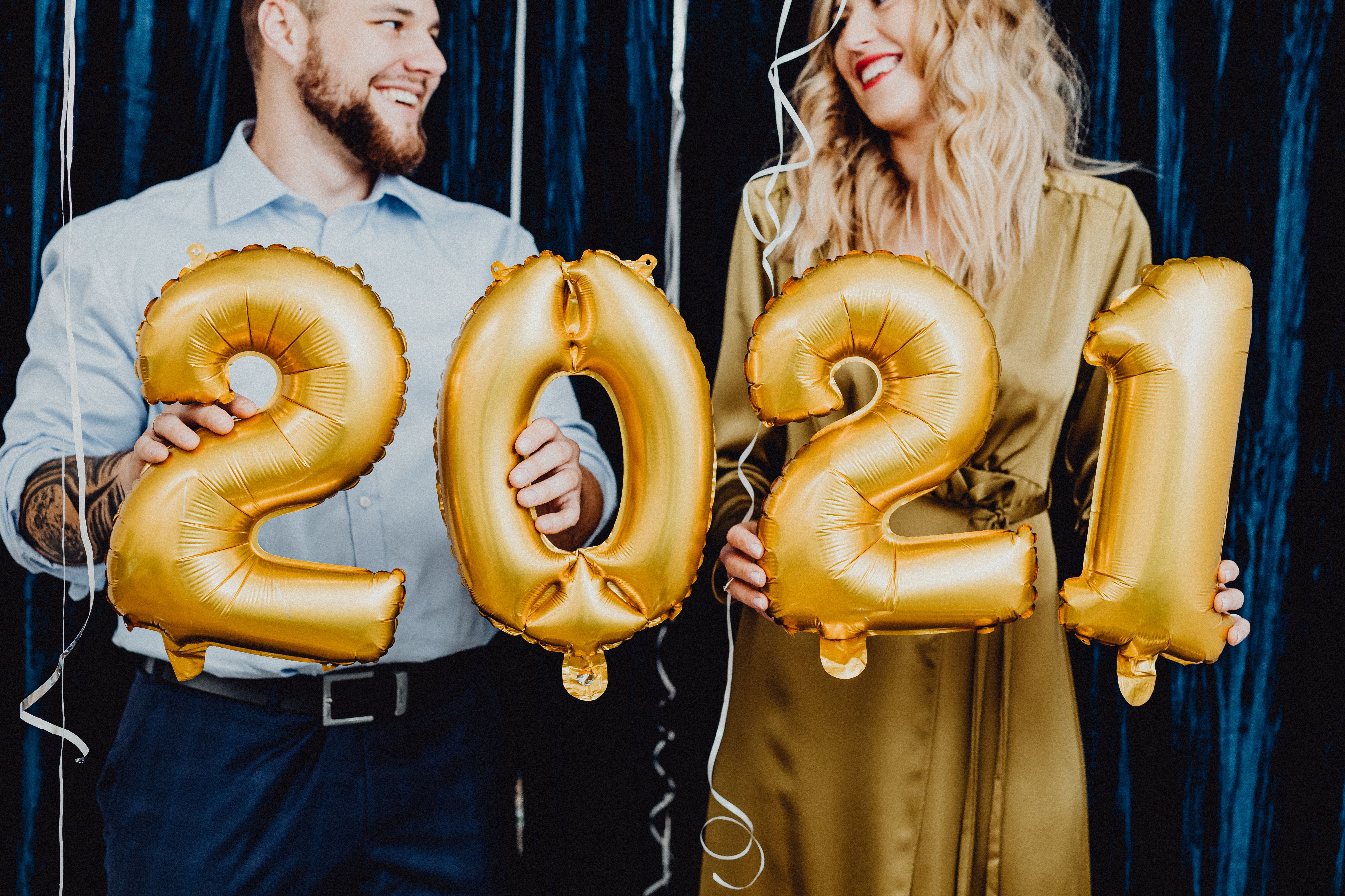 手持金气球的夫妇面带微笑，为2021年打造了喜庆的新年庆祝活动