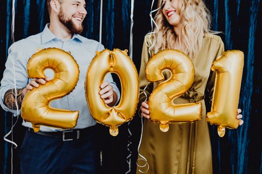 手持金气球的夫妇面带微笑，为2021年打造了喜庆的新年庆祝活动