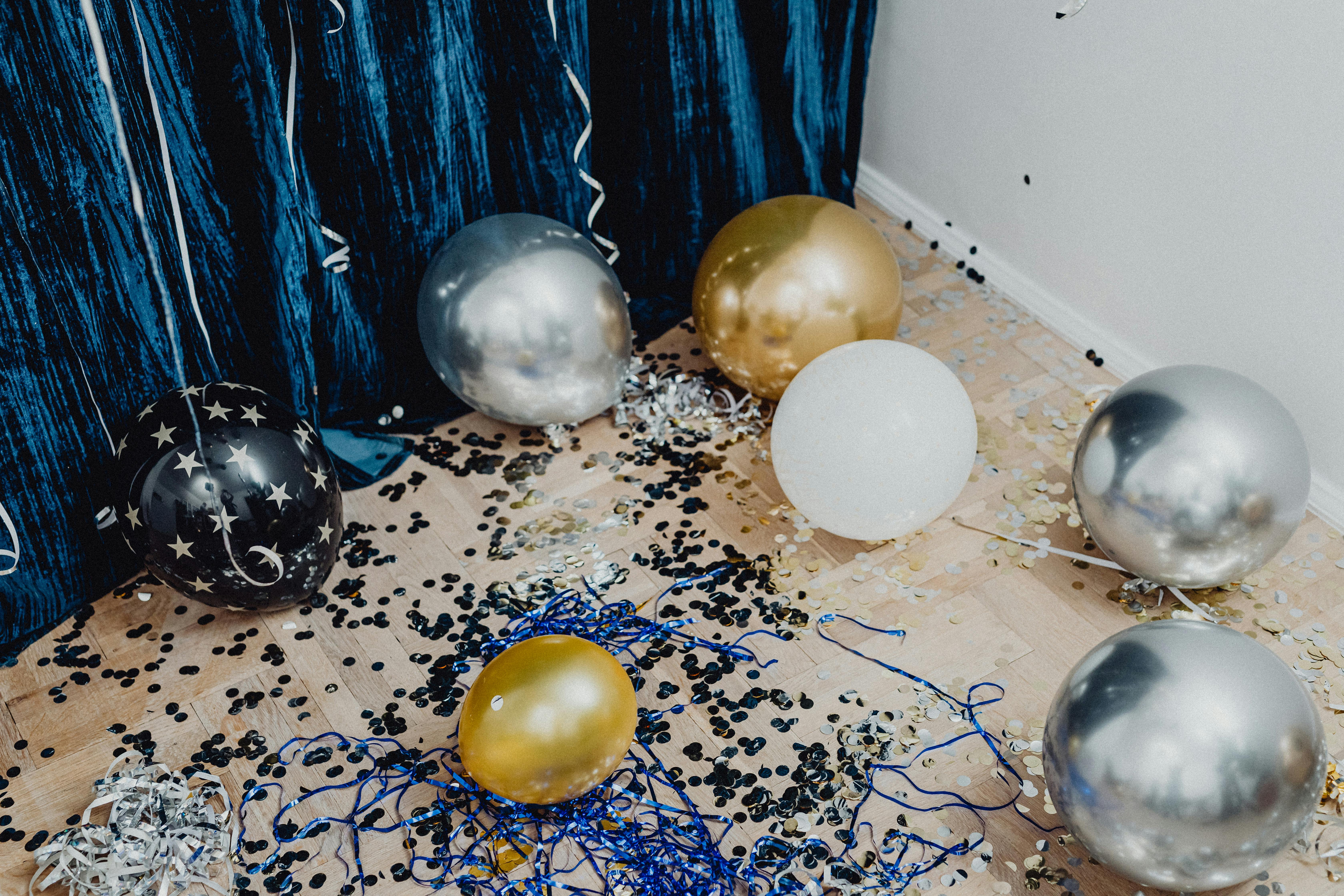 balloons on wooden floor near blue curtain