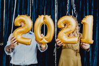 两个人举着金色气球庆祝2021年的节日