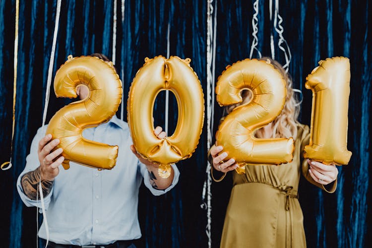 Two People Holding 2021 Golden Balloons