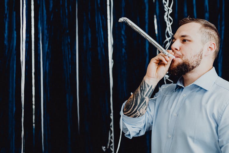 Man In Blue Long Sleeve Shirt Blowing A Party Horn