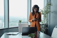 Woman in Orange Coat Standing in Front of Black Laptop Computer