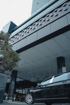 一辆豪华汽车停放在城市环境中现代摩天大楼立面的低角度视图里