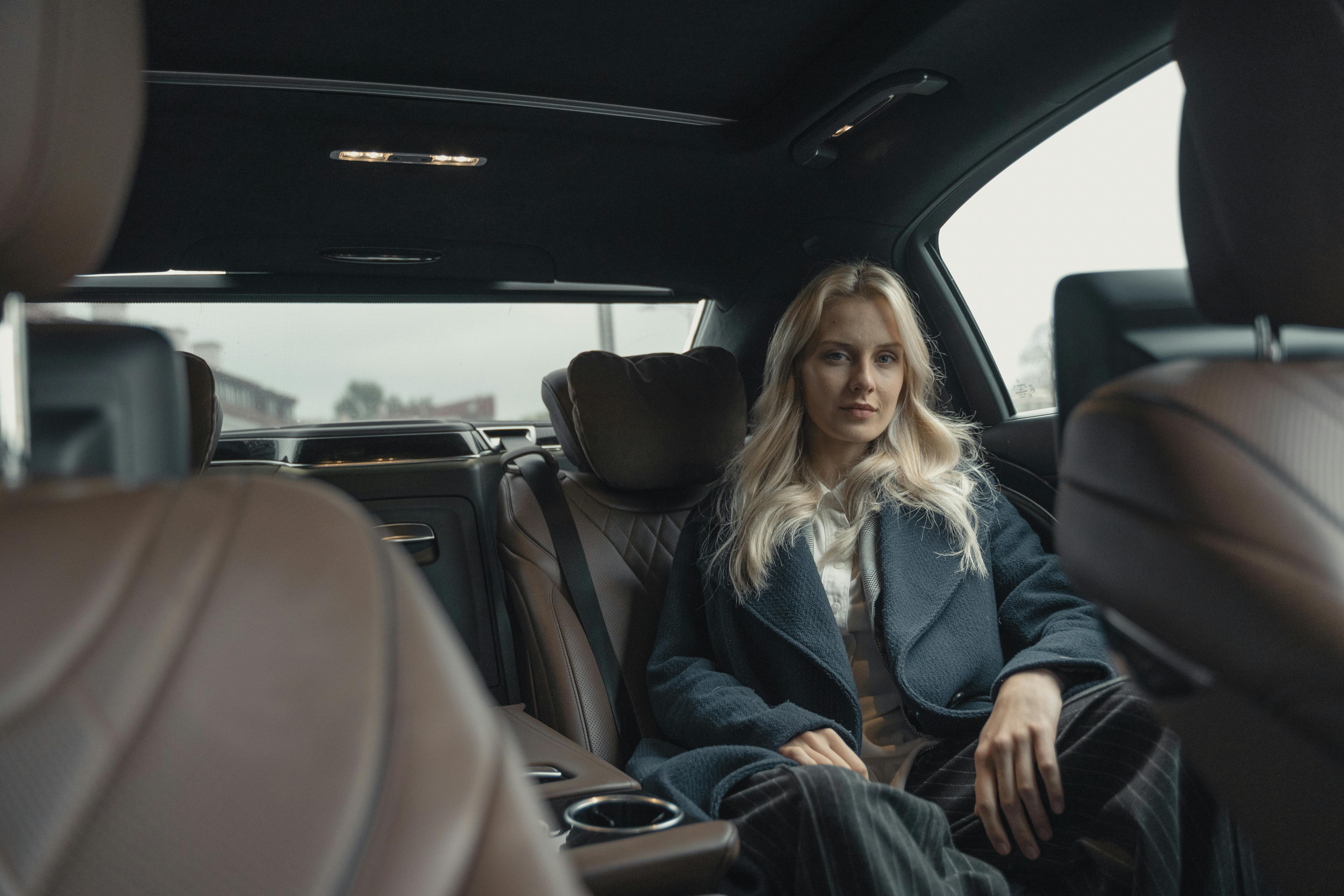 woman in blue coat sitting on back seat of a car