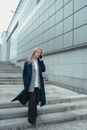 一位自信的女商人穿着蓝色外套，在现代建筑外打电话