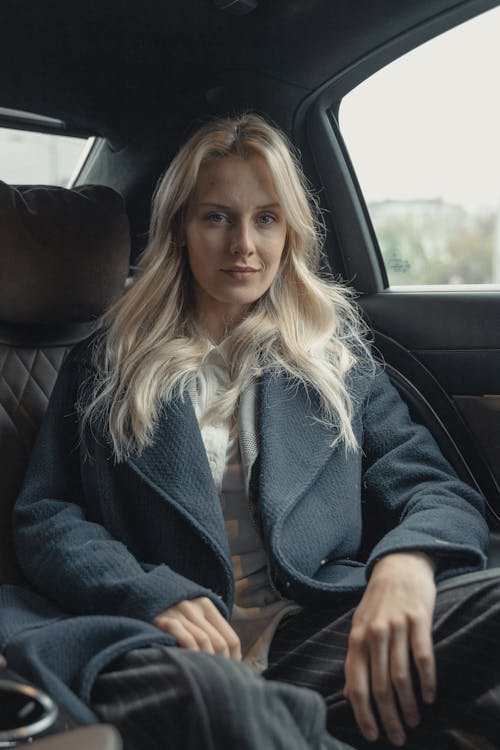 Woman in Blue Coat Sitting on Back Seat of a Car