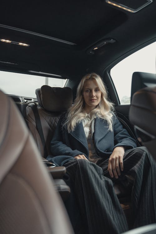 Pretty Woman in Blue Coat Sitting on Back Seat of a Car