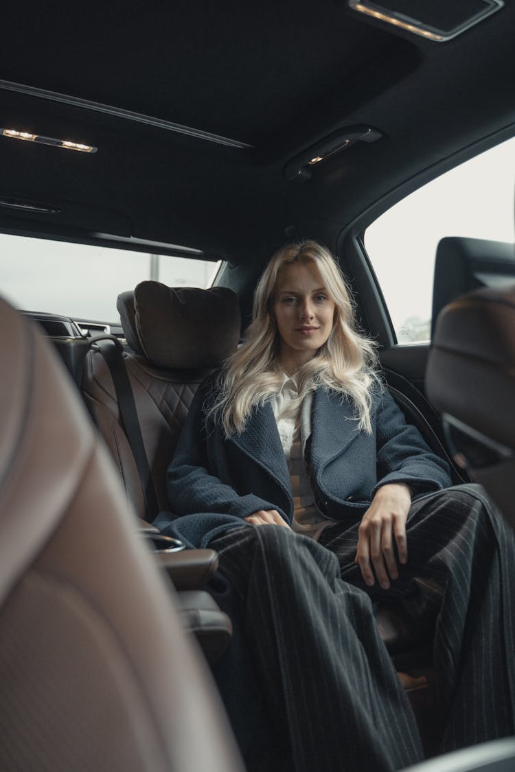 Pretty Woman In Blue Coat Sitting On Back Seat Of A Car