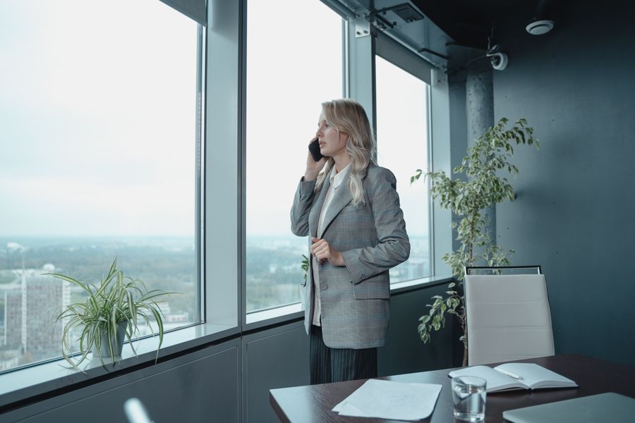 A professional woman in a gray blazer talks on the phone