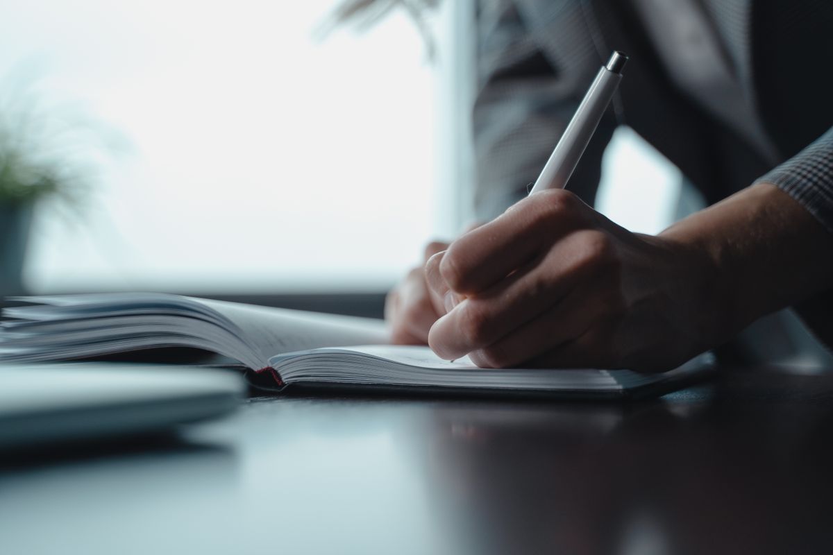 A person writing in a notebook with a pen