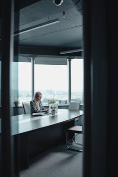 Businesswoman working on a laptop in a spacious and modern office setting.