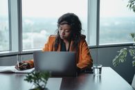 Woman in Orange Jacket Using Macbook