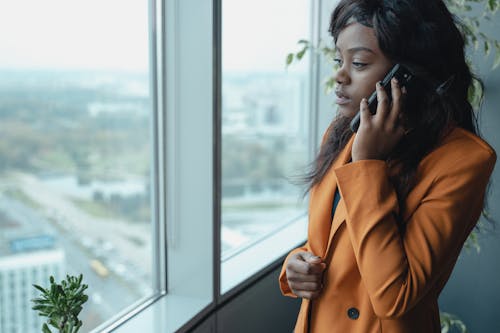 Woman in Brown Coat Holding Black Smartphone