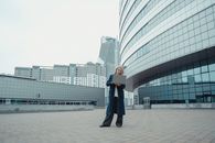 一名穿着蓝色外套的白人妇女在现代高层建筑外用笔记本电脑工作