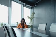 现代办公室里，一位黑人女商人正用笔记本电脑打电话