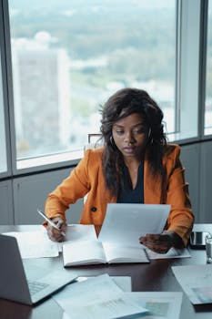 Professional woman in a bright office reviewing paperwork. Productivity and focus in a business setting.