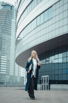 Stylish businesswoman walking with confidence in front of a modern glass building.