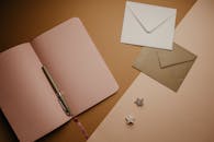 一个时尚的平面上摆放着打开的笔记本电脑、信封和一支笔，是文具爱好者的完美选择