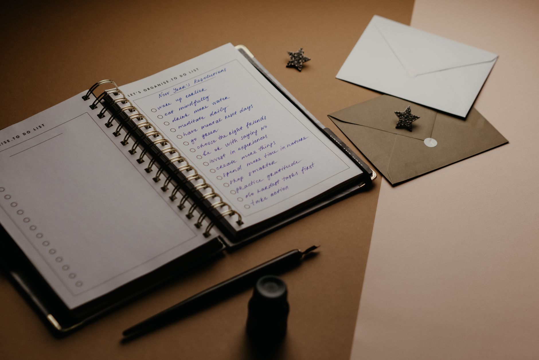A tidy desk setup featuring a planner, to-do list, envelopes, and a pen.