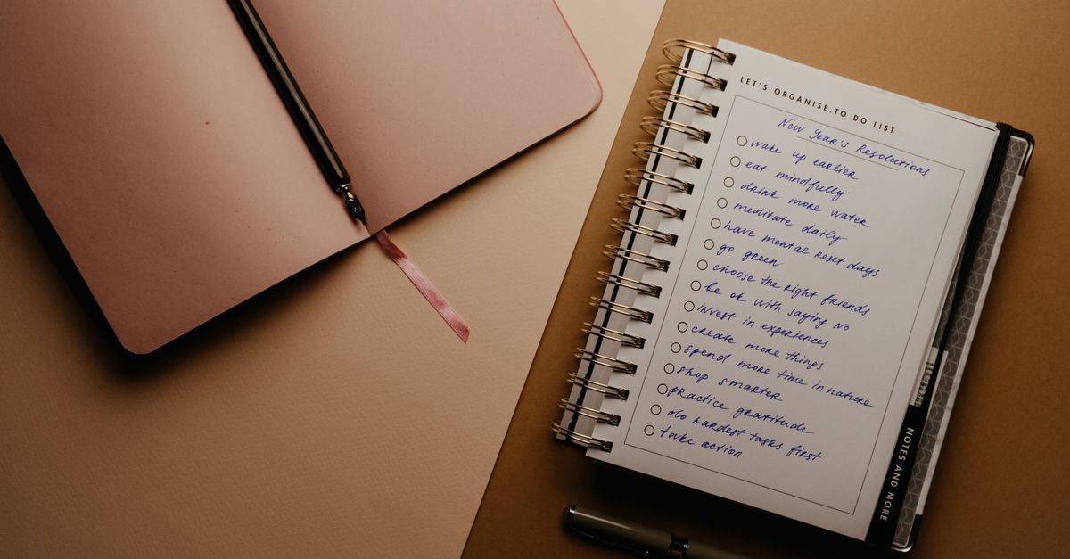 open journal with handwritten morning priority next to a glass of water