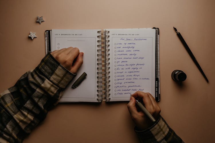 Hands Writing New Year's Resolutions 