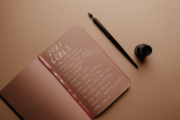 A person writing their goals in a notebook with strong determination