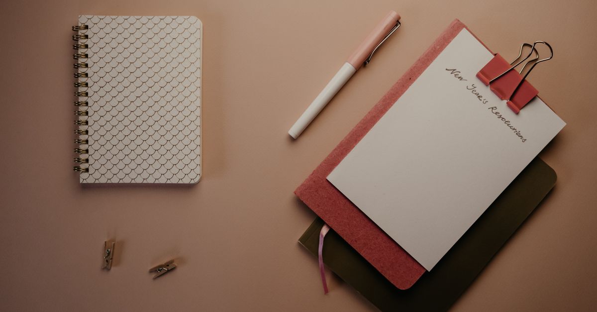 Organized flatlay of notebooks and pen on a clean desk for new year planning