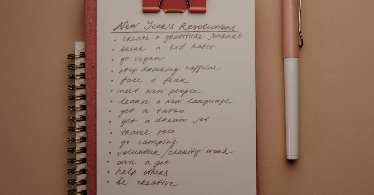 Top view of a notebook with New Year's resolutions and a pen on a neutral background.