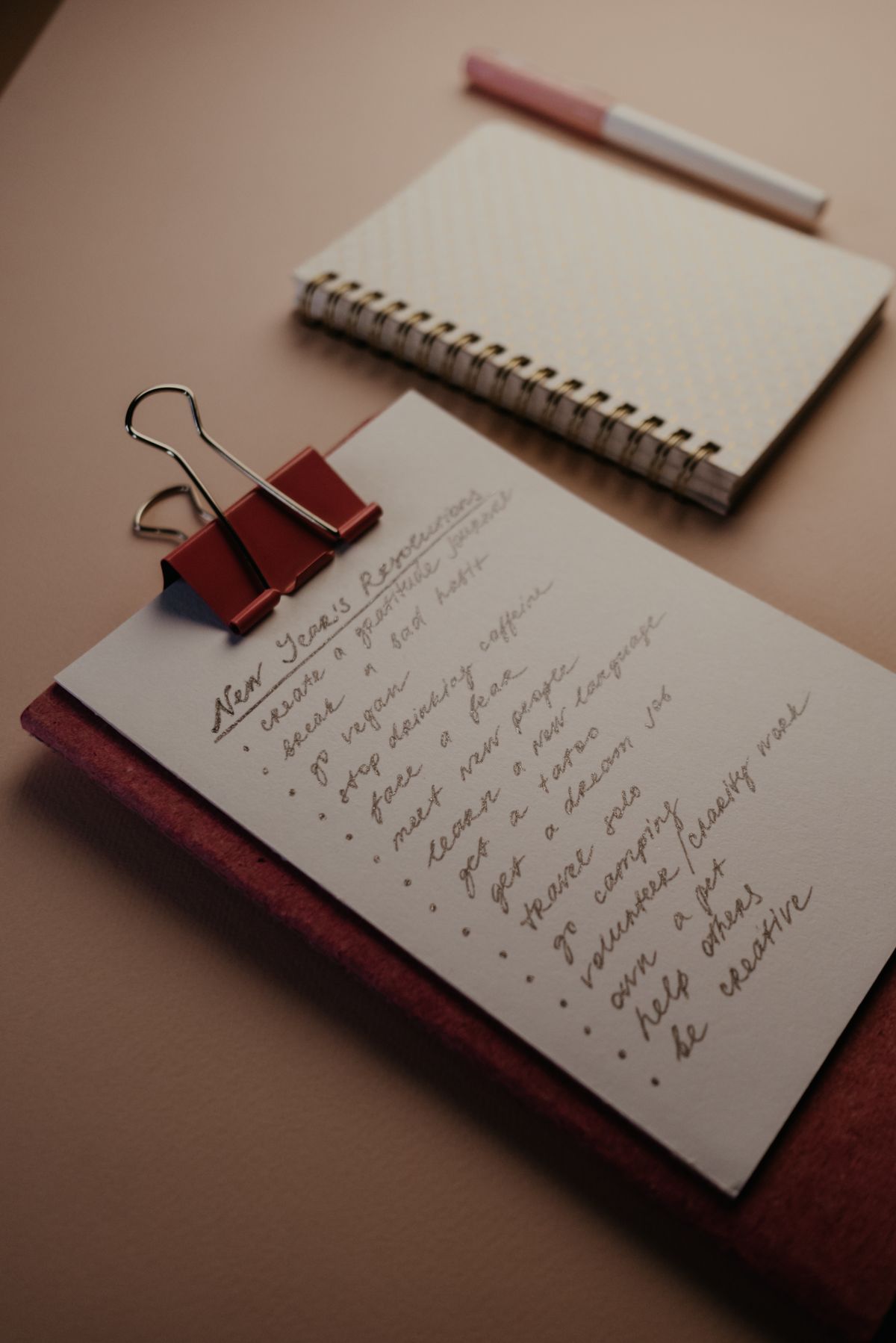 Caderno com lista curta de prioridades e caneta para planejar o mês sem excesso de cobrança