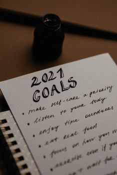 在舒适的环境中，用墨水瓶和自来水笔在纸上拍摄了2021年目标清单的特写