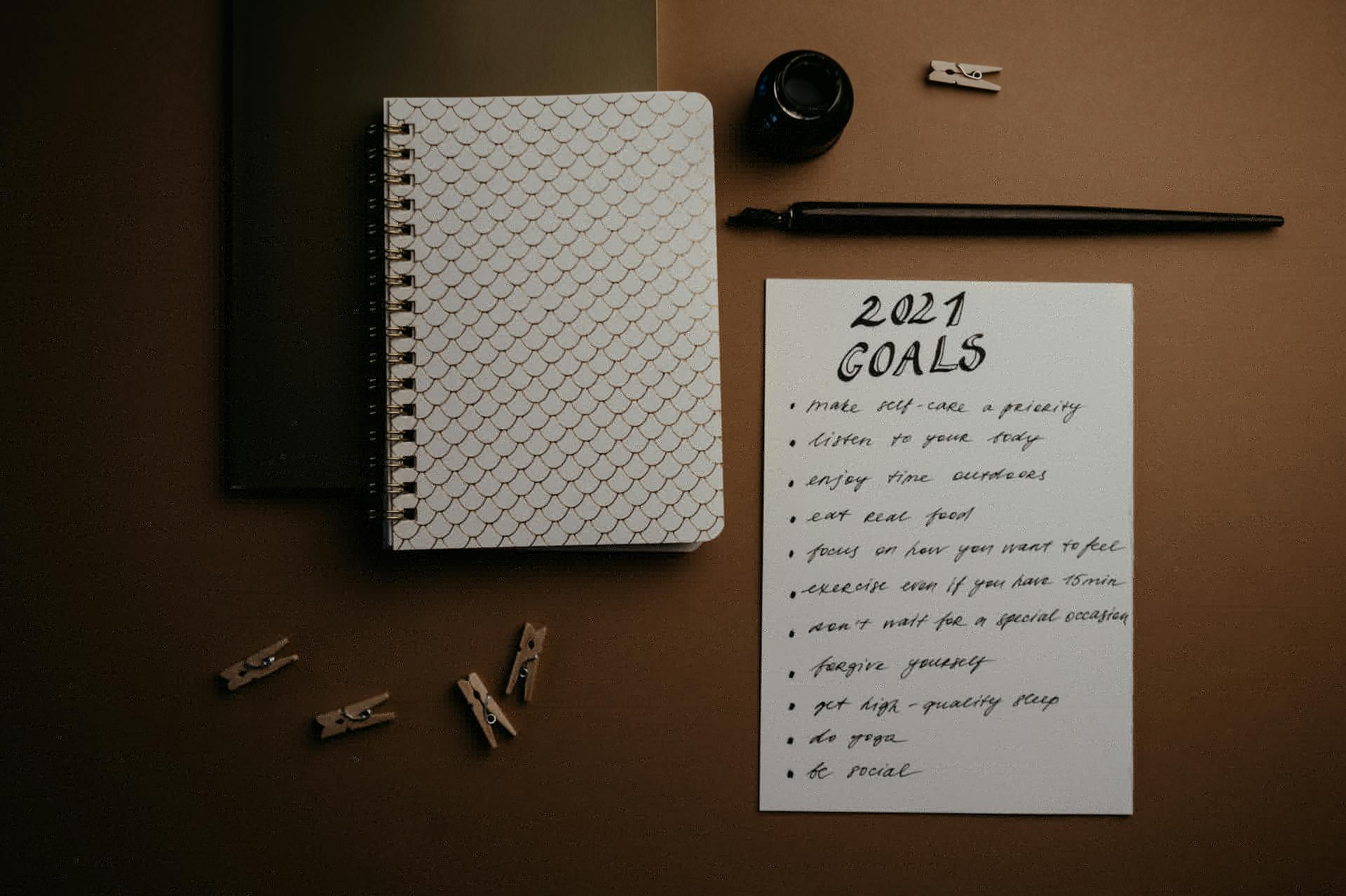 Aesthetic flatlay of notebooks and a 2021 goals list in elegant calligraphy.