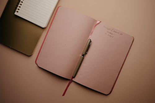 Pink Notebook With Pen on the Table