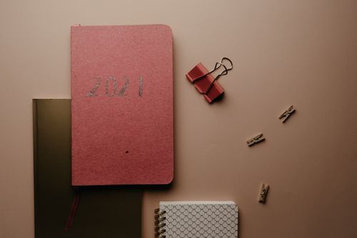 Free Aesthetic flat lay of 2021 planner with office supplies on a brown background. Stock Photo