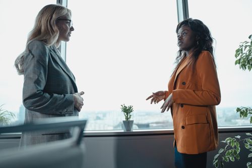 Free Two professional women in a corporate office having a conversation by the window. Stock Photo