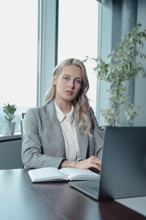 Free Woman in Gray Blazer Sitting by the Table With Laptop Computer Stock Photo