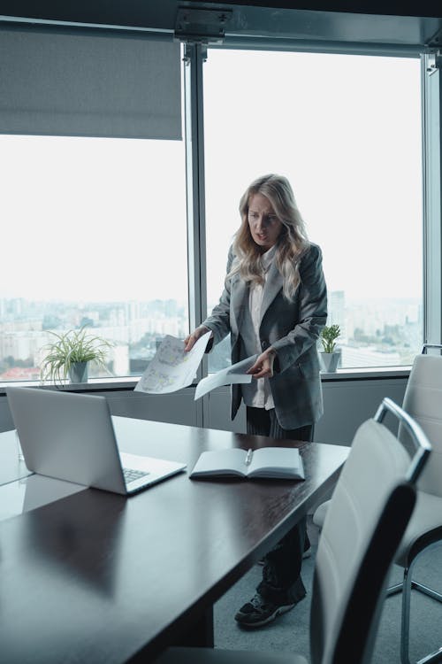 Free Woman in Gray Blazer Standing Beside Table Stock Photo