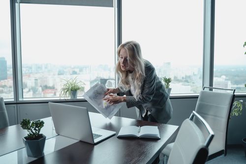 Free Professional businesswoman in modern office conducting virtual meeting with documents and laptop. Stock Photo