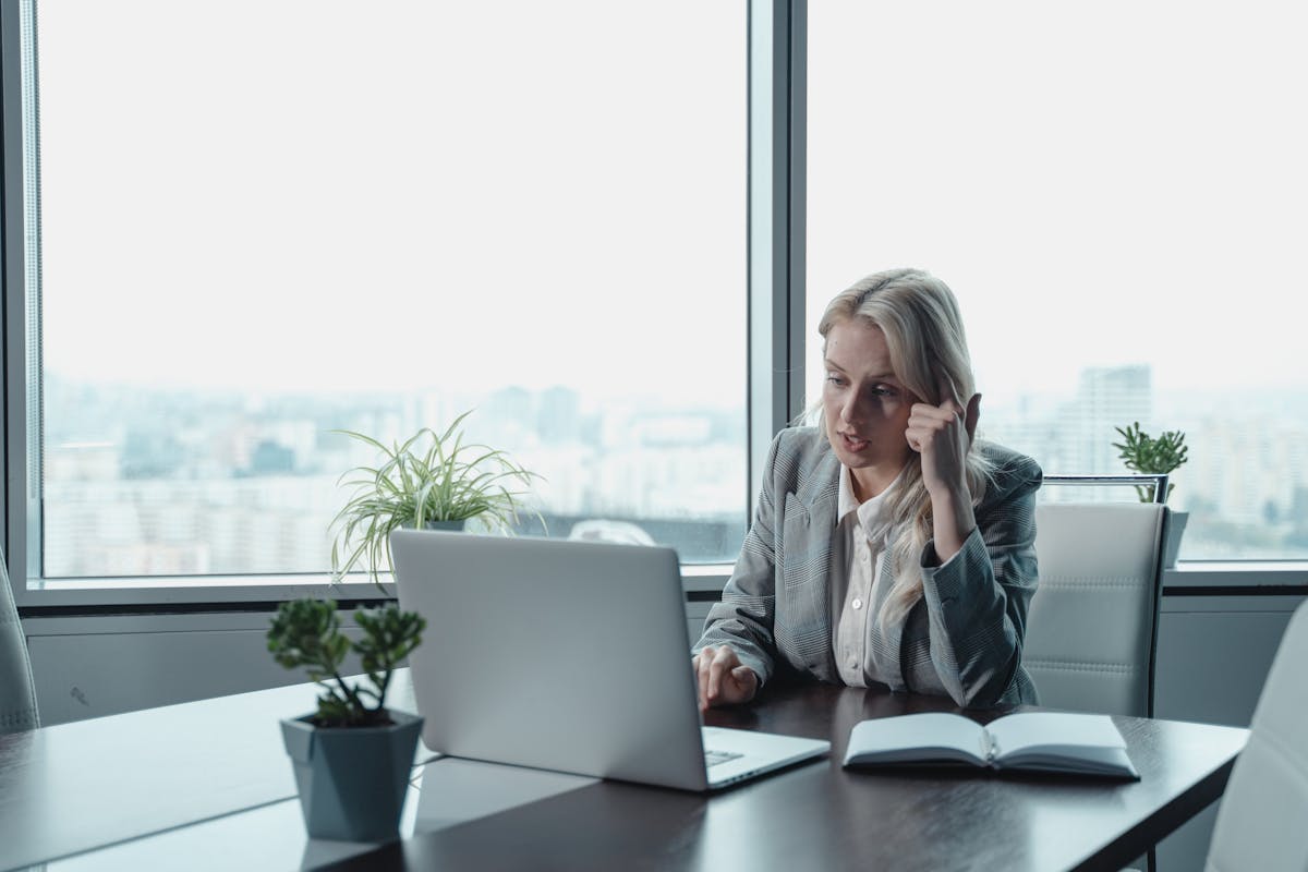 Professional woman working thoughtfully at her desk with laptop