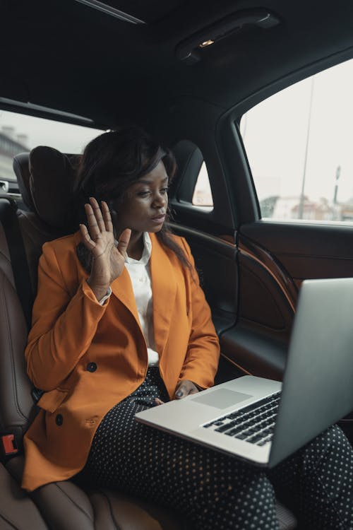 Woman In Orange Blazer Sitting Inside A Car