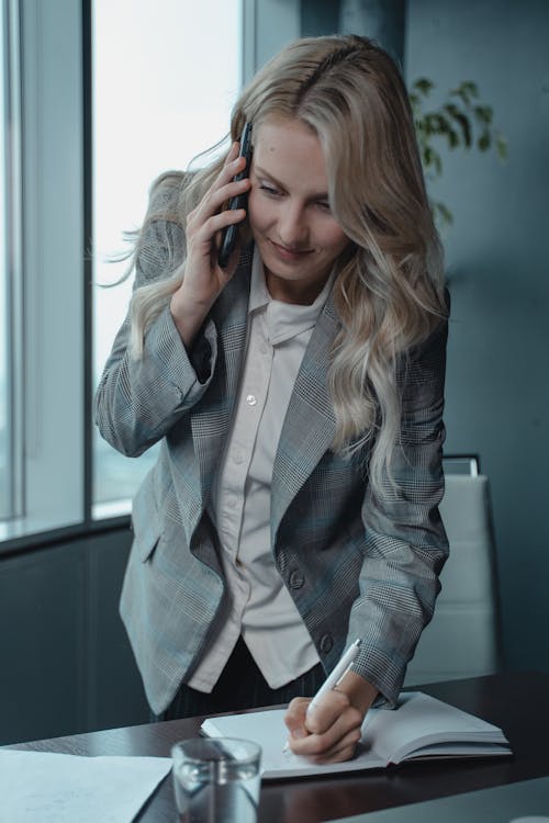 Free Woman In Gray Blazer Holding Phone To Her Ear Stock Photo